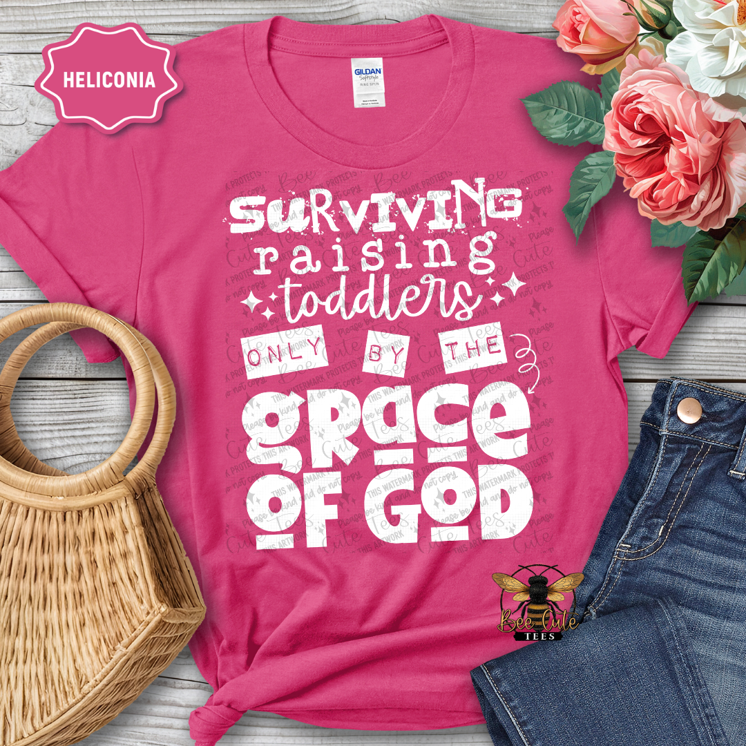 Pink t-shirt with humorous text design on a wooden surface with flowers and denim jeans.
