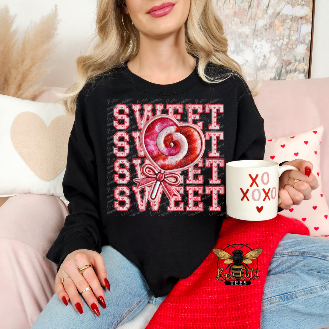 Person wearing a black sweatshirt with a candy graphic and holding a mug, sitting on a couch.