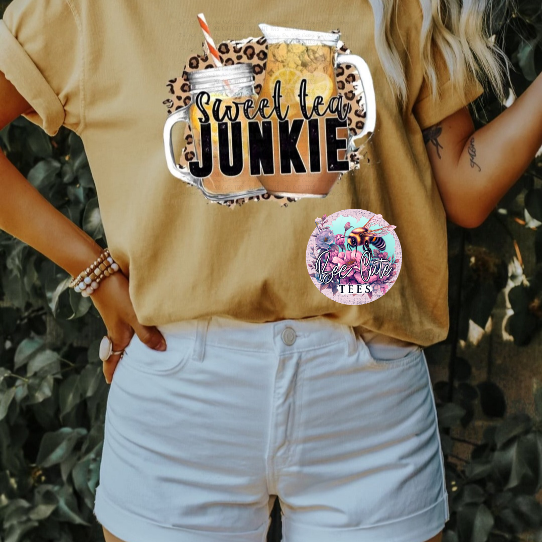 Person wearing a yellow shirt with 'Sweet Tea Junkie' graphic and white shorts, standing outdoors.