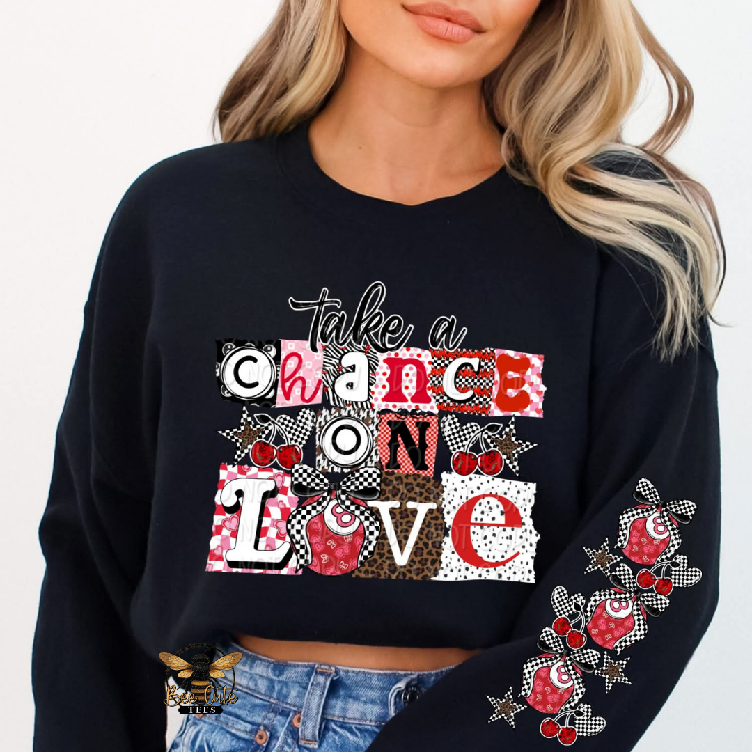 Black sweatshirt with colorful text design and floral embroidery on sleeves, worn by a person.