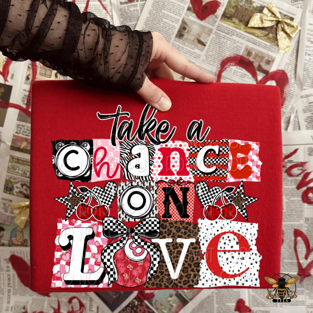 Red fabric with 'Take a chance on love' text held over newspaper background
