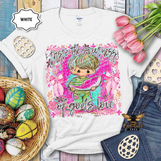 White t-shirt with colorful graphic design featuring a child holding watermelon, surrounded by Easter eggs and flowers.