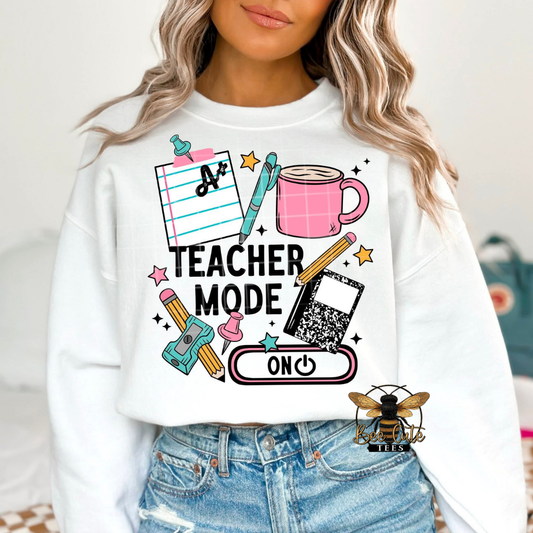 Person wearing a white sweatshirt with 'Teacher Mode On' graphic design.