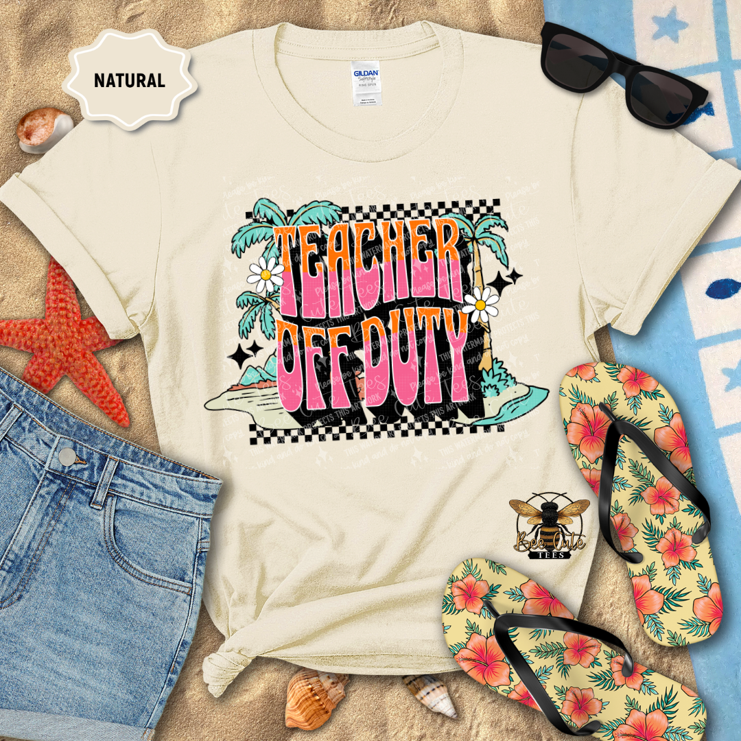 Beige t-shirt with 'Teacher Off Duty' design on a beach-themed background with sunglasses, flip-flops, and denim shorts.