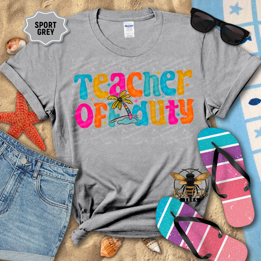 Gray t-shirt with 'Teacher on Duty' text in colorful letters, sunglasses, and flip-flops on a beach-themed background.