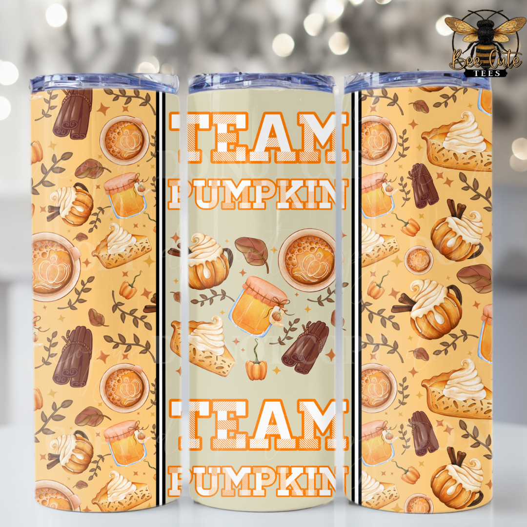 Three insulated tumblers with clear lids are shown from different angles to display a coordinated autumn pattern. The design features orange and brown text reading 'TEAM PUMPKIN' alongside illustrations of pumpkins, mugs, pie slices, and fall leaves on a warm beige background.