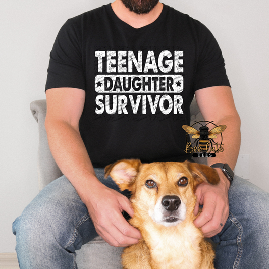 Person wearing a black t-shirt with 'TEENAGE DAUGHTER SURVIVOR' text, sitting with a dog.