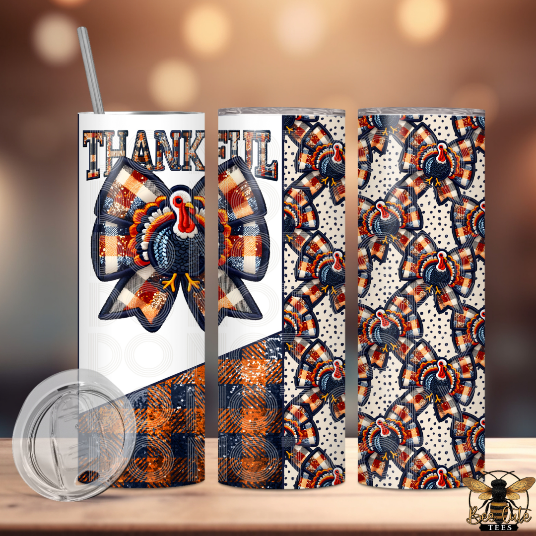 A 20 oz skinny tumbler shown in three wrap-around views with a clear lid and straw on a wooden surface against a warm blurred background. The design features a large bow-tie turkey motif with plaid wings, the word THANKFUL, and a repeating bow-tie turkey pattern on the sides.