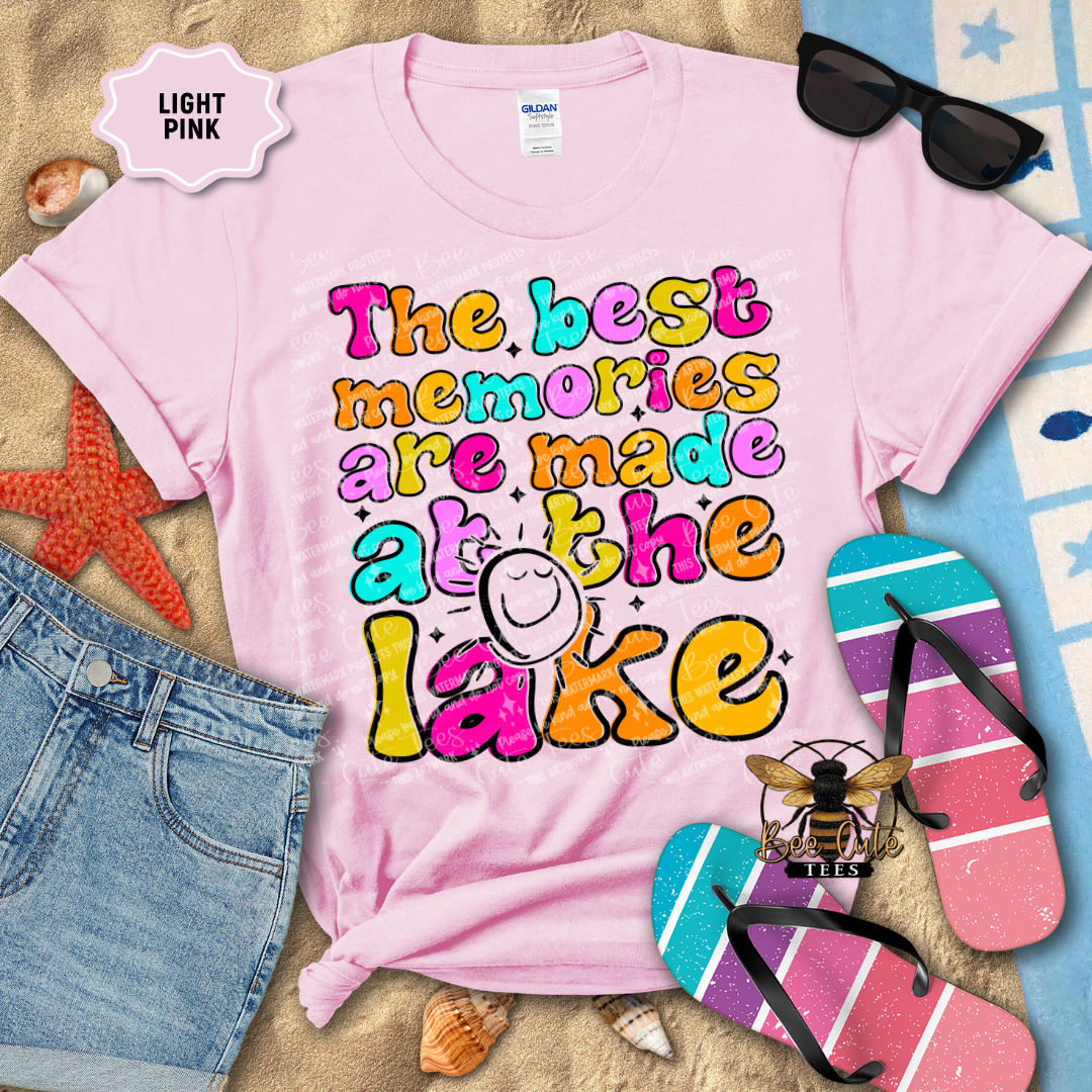 Light pink t-shirt with 'The best memories are made at the lake' text, surrounded by beach accessories.
