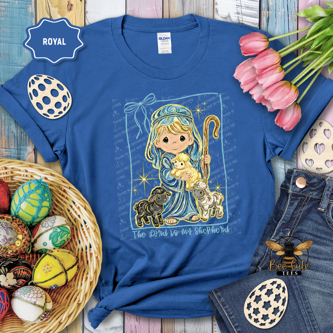 Blue t-shirt with a religious design featuring a shepherd and lamb, surrounded by Easter decorations.