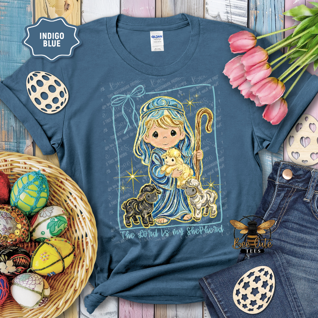 Blue t-shirt with a religious design featuring a shepherd and lamb, surrounded by Easter decorations.