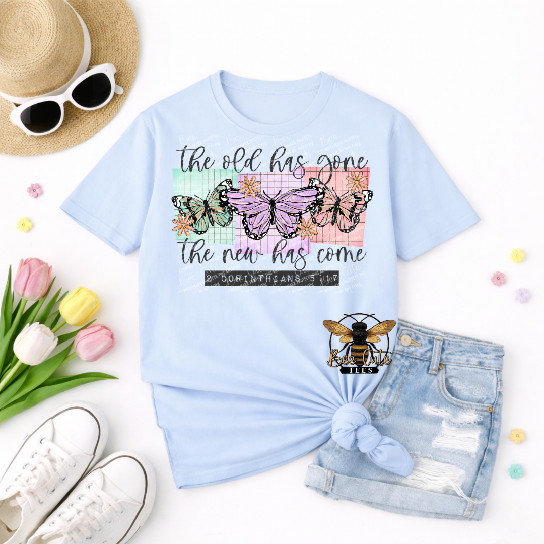 Light blue t-shirt with butterfly design and text, surrounded by accessories on a white background