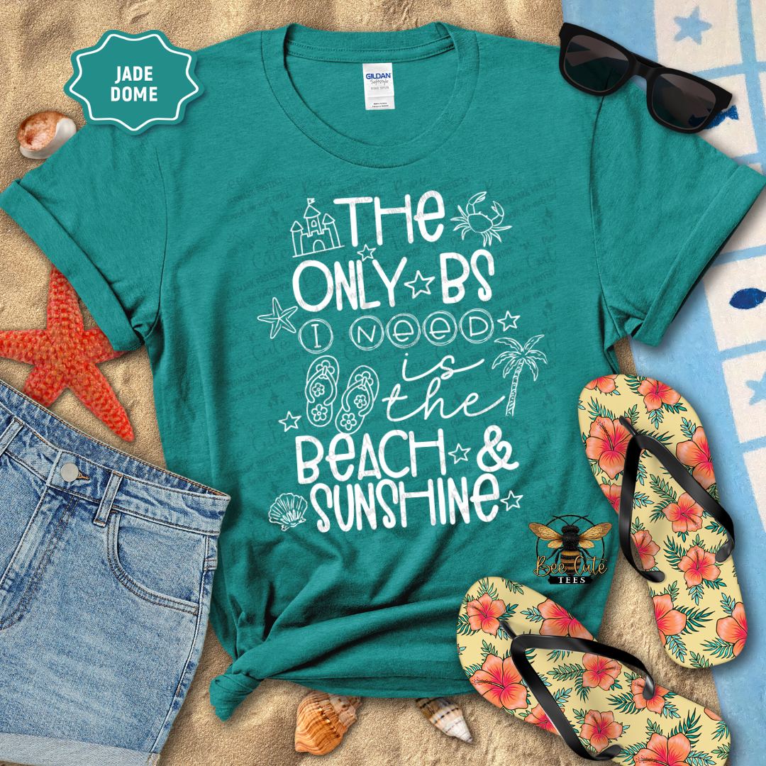 Teal t-shirt with beach-themed design, sunglasses, flip-flops, and denim shorts on a sandy background.