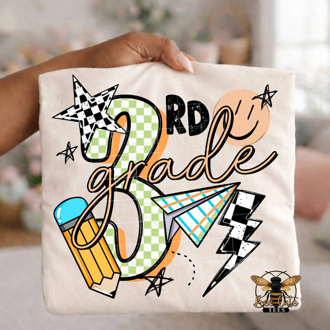 Folded white-colored unisex T-shirt held up by a hand, featuring a colorful "3rd Grade" graphic. The design includes green checkered number four, bold black lettering, peach script, a pencil, paper airplane, smiley face, lightning bolt, stars, and playful doodles. A fun, retro-inspired back-to-school design perfect for fourth grade teachers and students.
