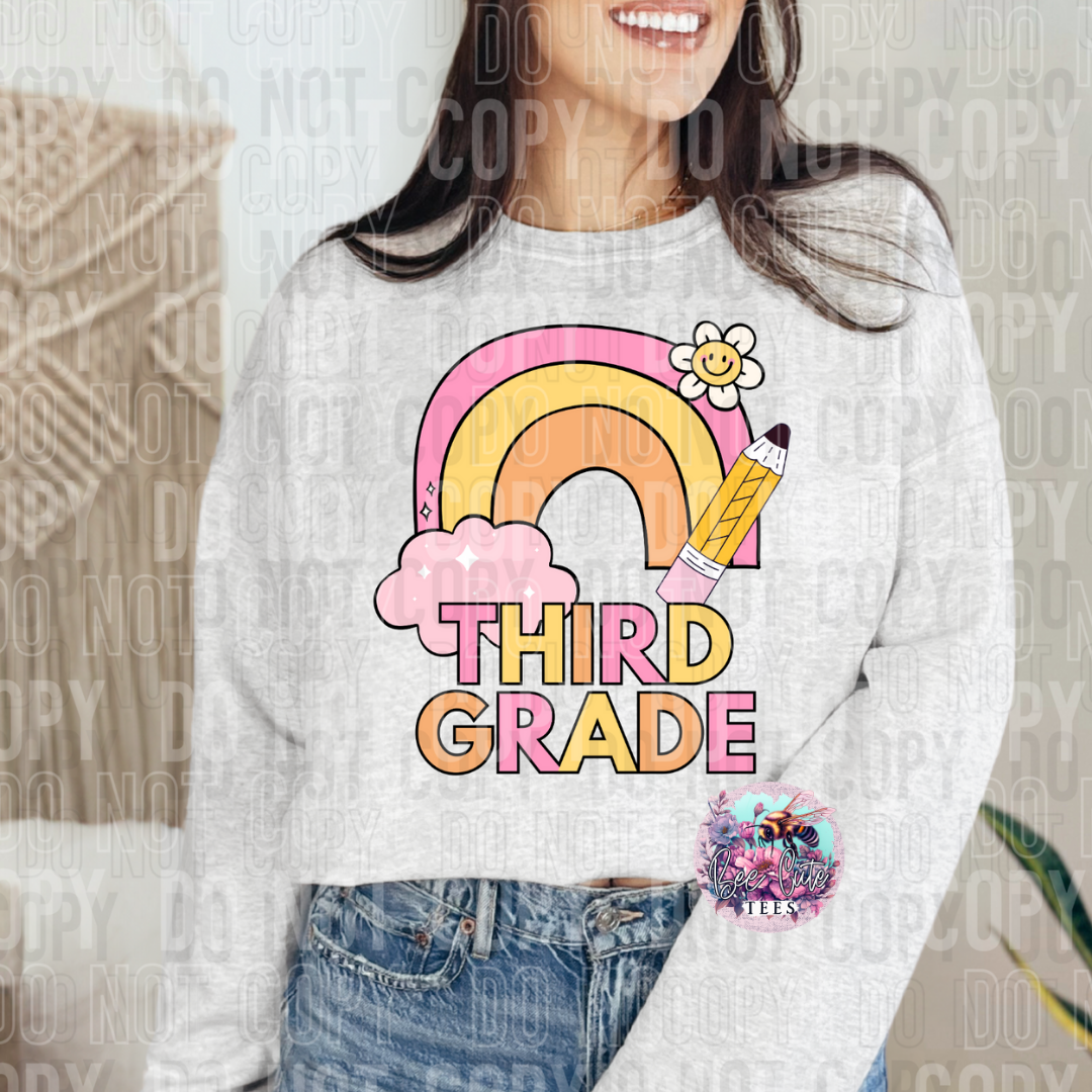 Person wearing a sweatshirt with a 'Third Grade' design featuring a rainbow and pencil.