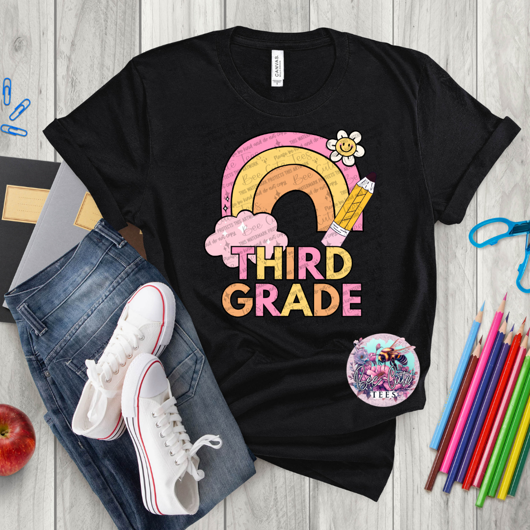 Black t-shirt with 'Third Grade' design on a wooden surface with school supplies.