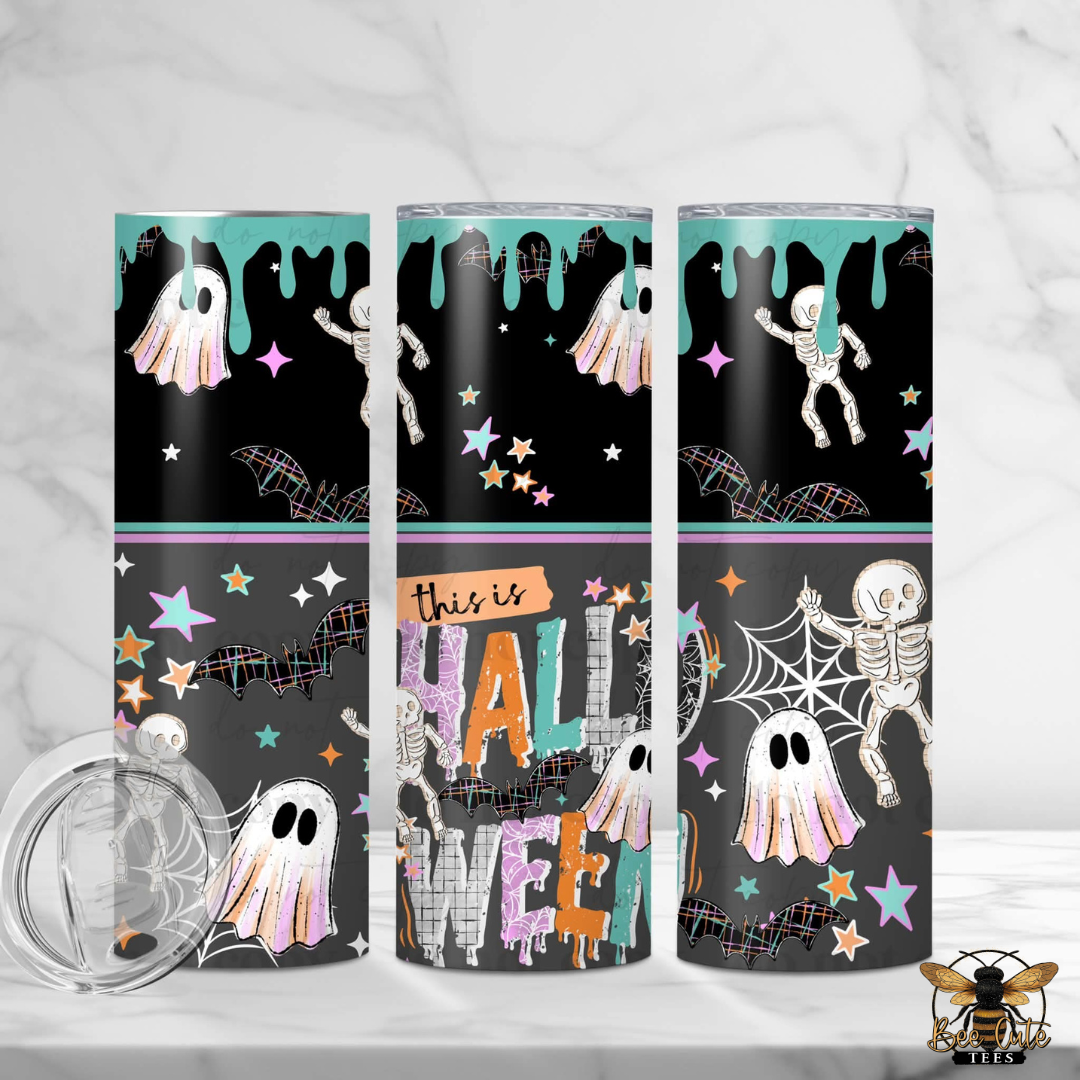 Three tall skinny tumblers with Halloween-themed wrap designs are displayed on a light marble surface. The designs feature black backgrounds with teal dripping accents, white ghosts, white skeletons, colorful stars, spiderwebs, and the words 'this is HALLOWEEN' in large decorative letters.
