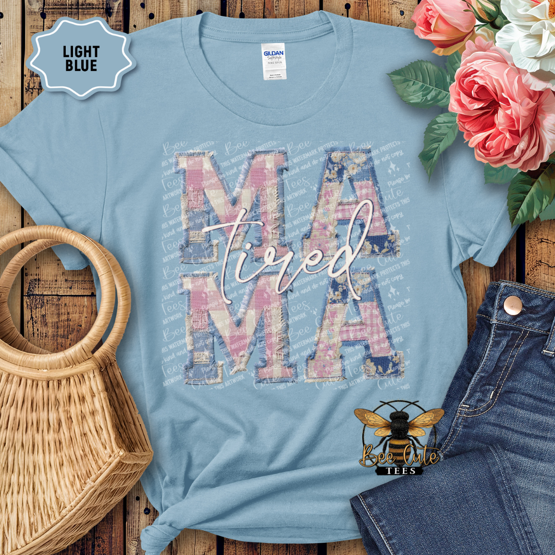 Light blue t-shirt with 'Mama' design on a wooden surface with flowers and jeans.