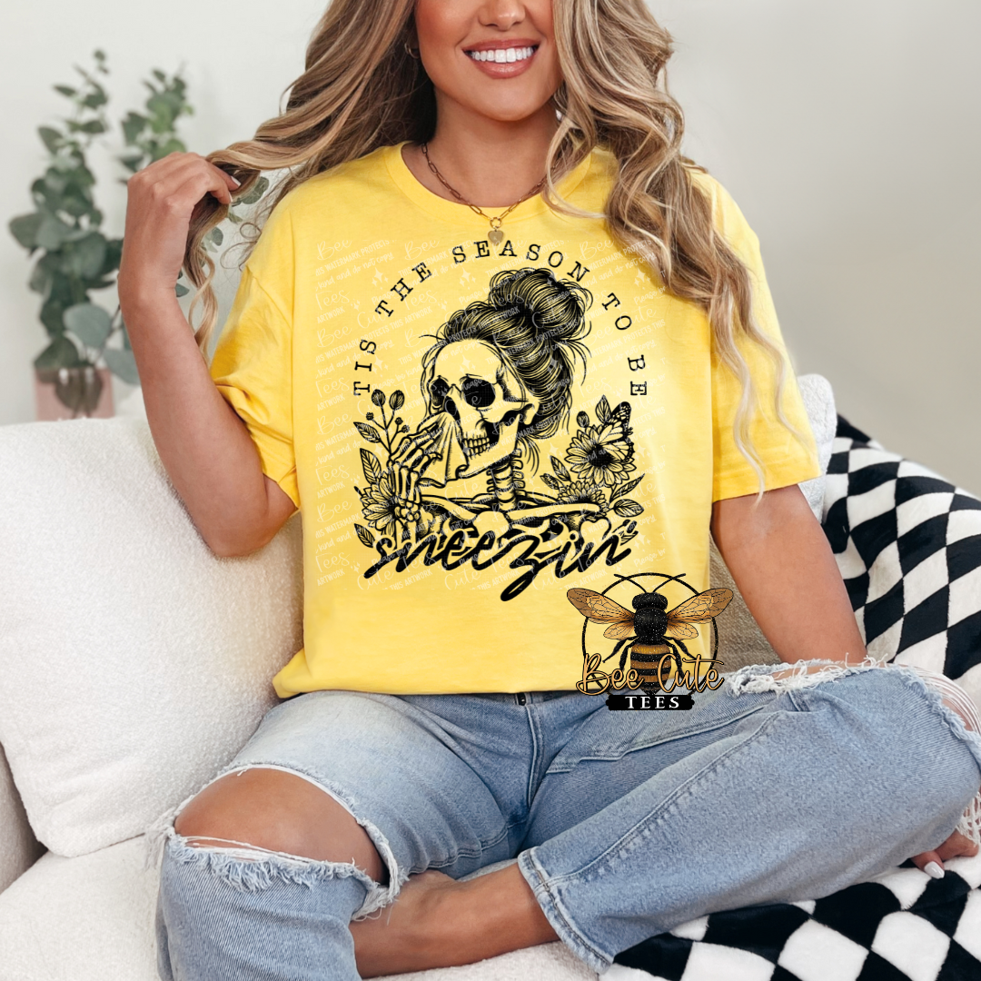 Person wearing a yellow t-shirt with a graphic design sitting on a couch.