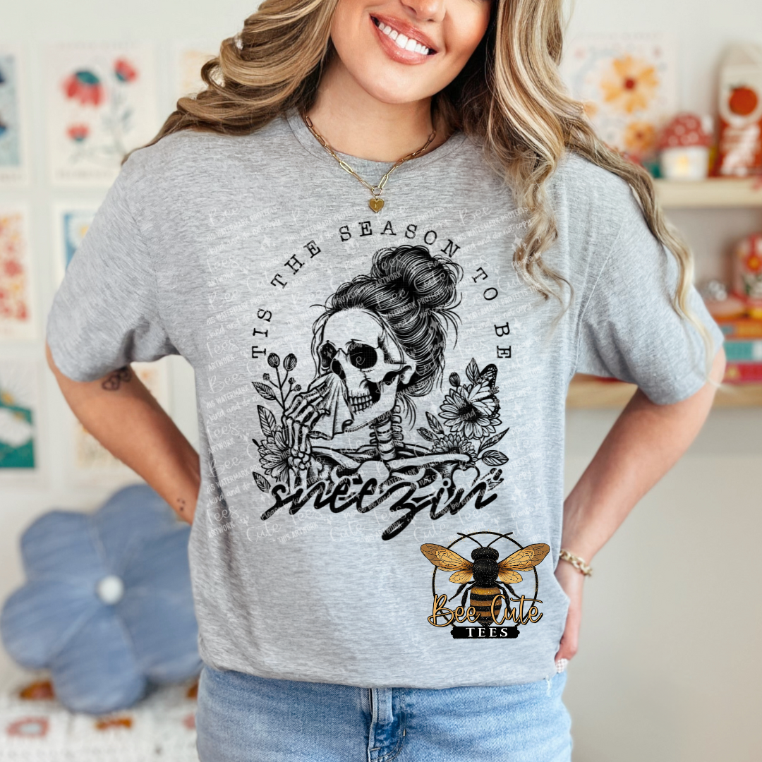 Woman wearing a gray t-shirt with a graphic design and text, standing in a casual setting.