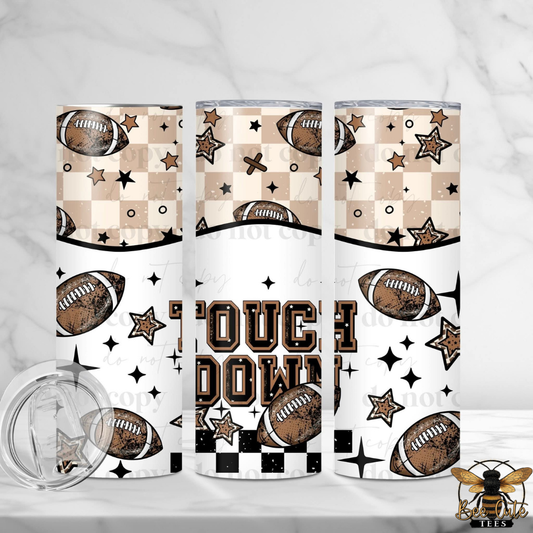 Three insulated tumblers with a football-themed pattern featuring brown footballs, beige and black checkered sections, black stars, and the words 'TOUCH DOWN' on a white background. A clear lid is shown in the lower left, and a bee logo with 'Tees' appears in the lower right.