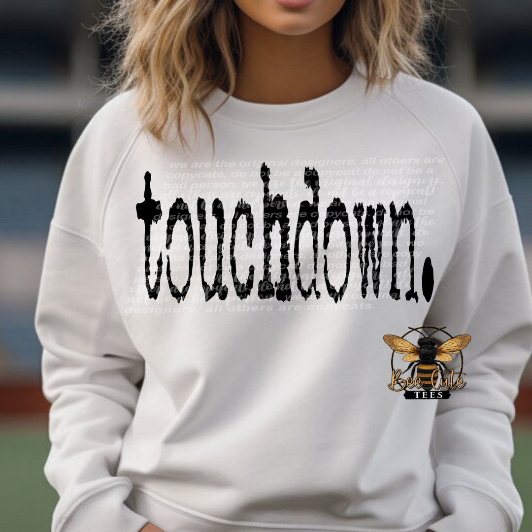 White crewneck sweatshirt featuring distressed black “touchdown.” text, shown on a model for a casual, sporty look.
