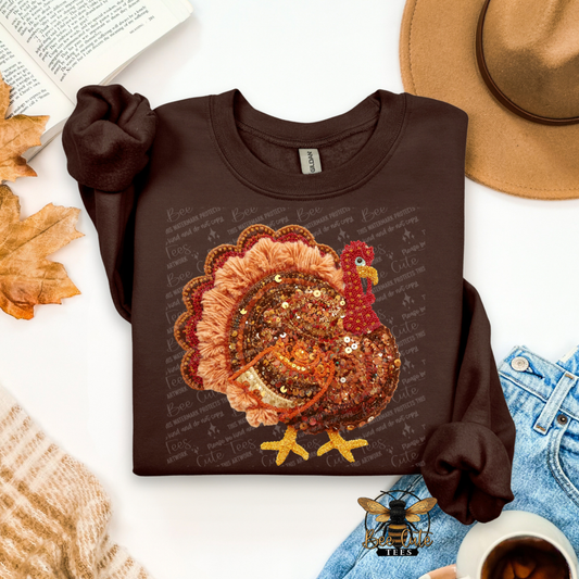 Brown sweatshirt with a turkey design on a white surface with autumn leaves and a hat.