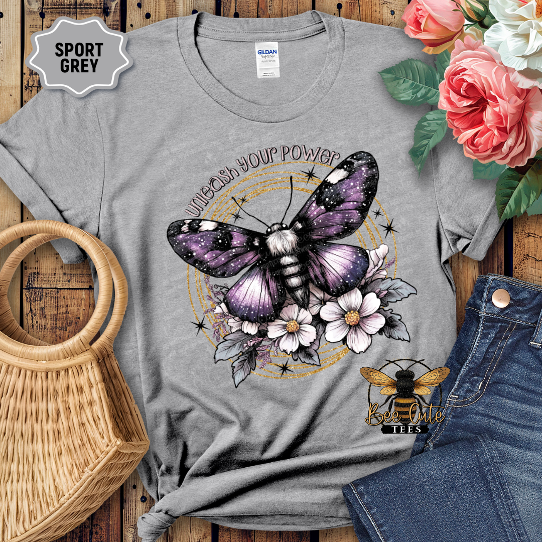 Gray t-shirt with butterfly and flower design on a wooden surface with flowers and jeans.