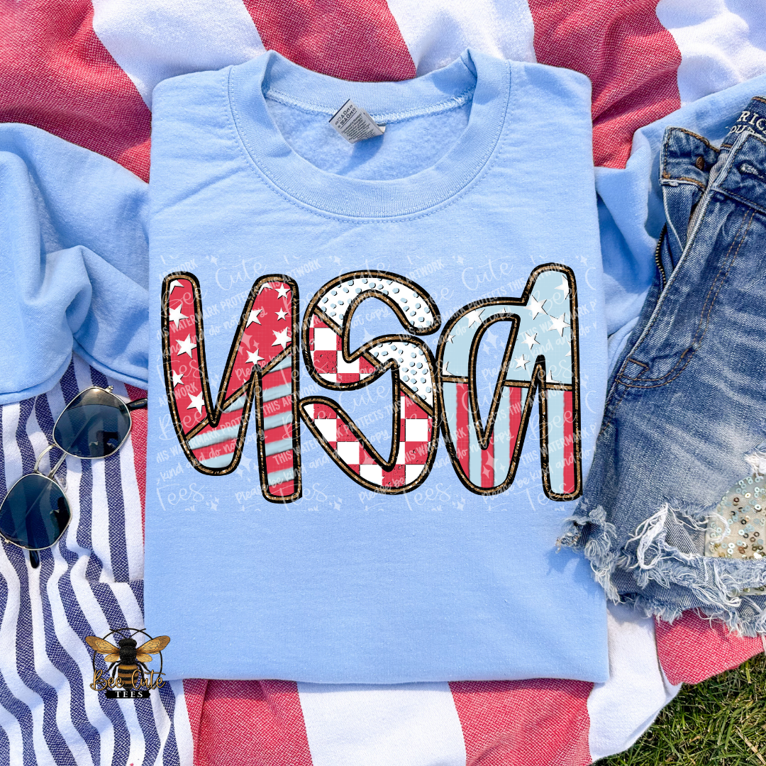 Light blue t-shirt with 'USA' text in American flag design on a flag background