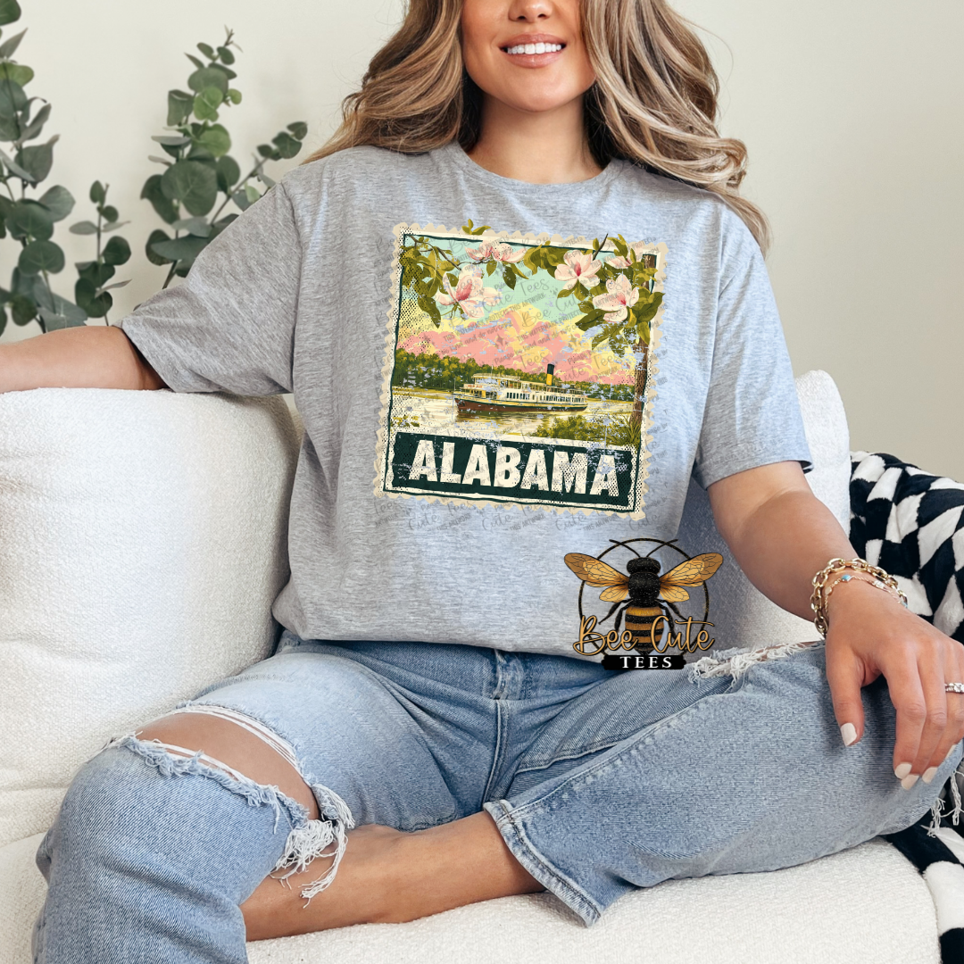 Person wearing a gray t-shirt with a 'Alabama' graphic design sitting on a couch.