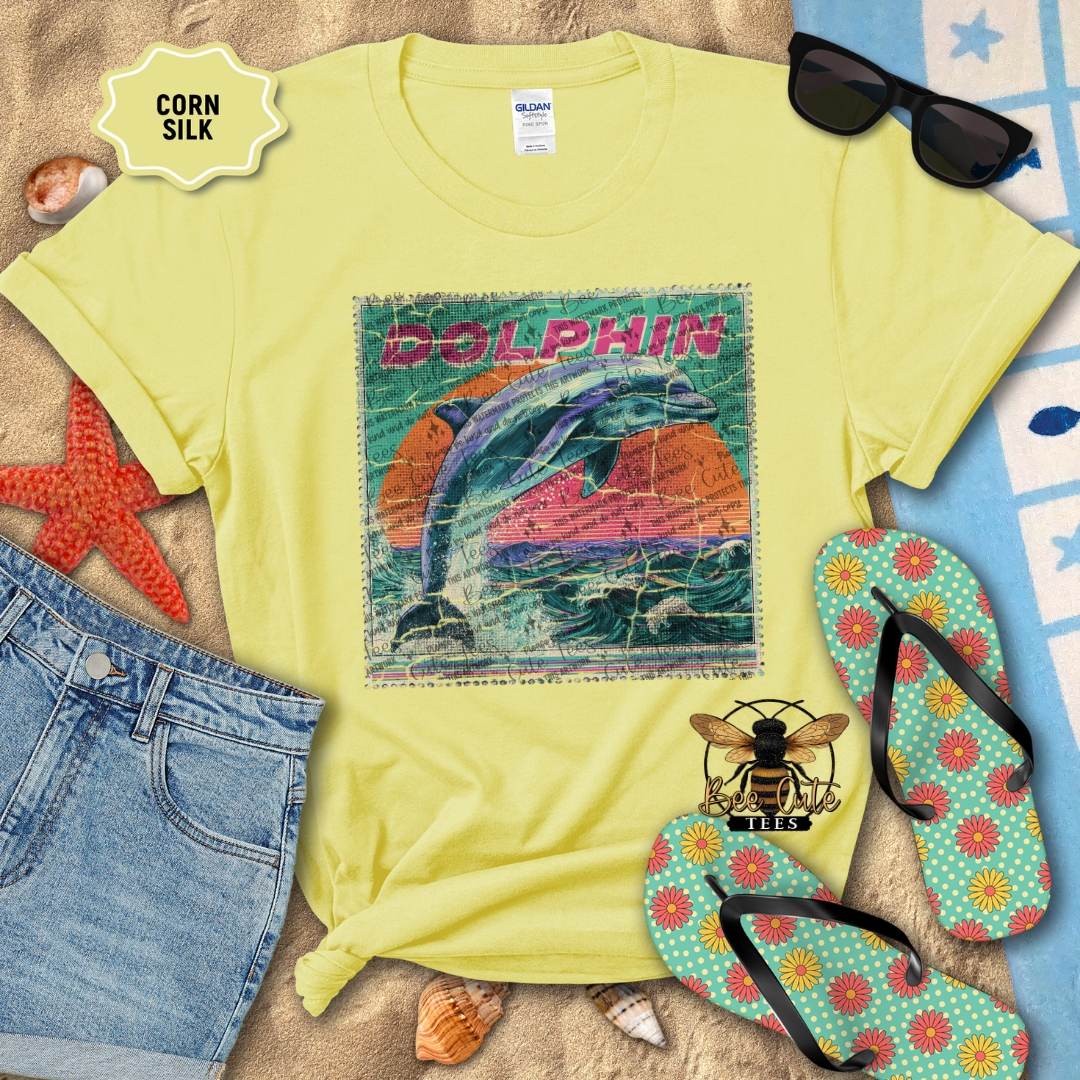 Yellow t-shirt with dolphin graphic, sunglasses, flip-flops, and denim shorts on a beach-themed background.