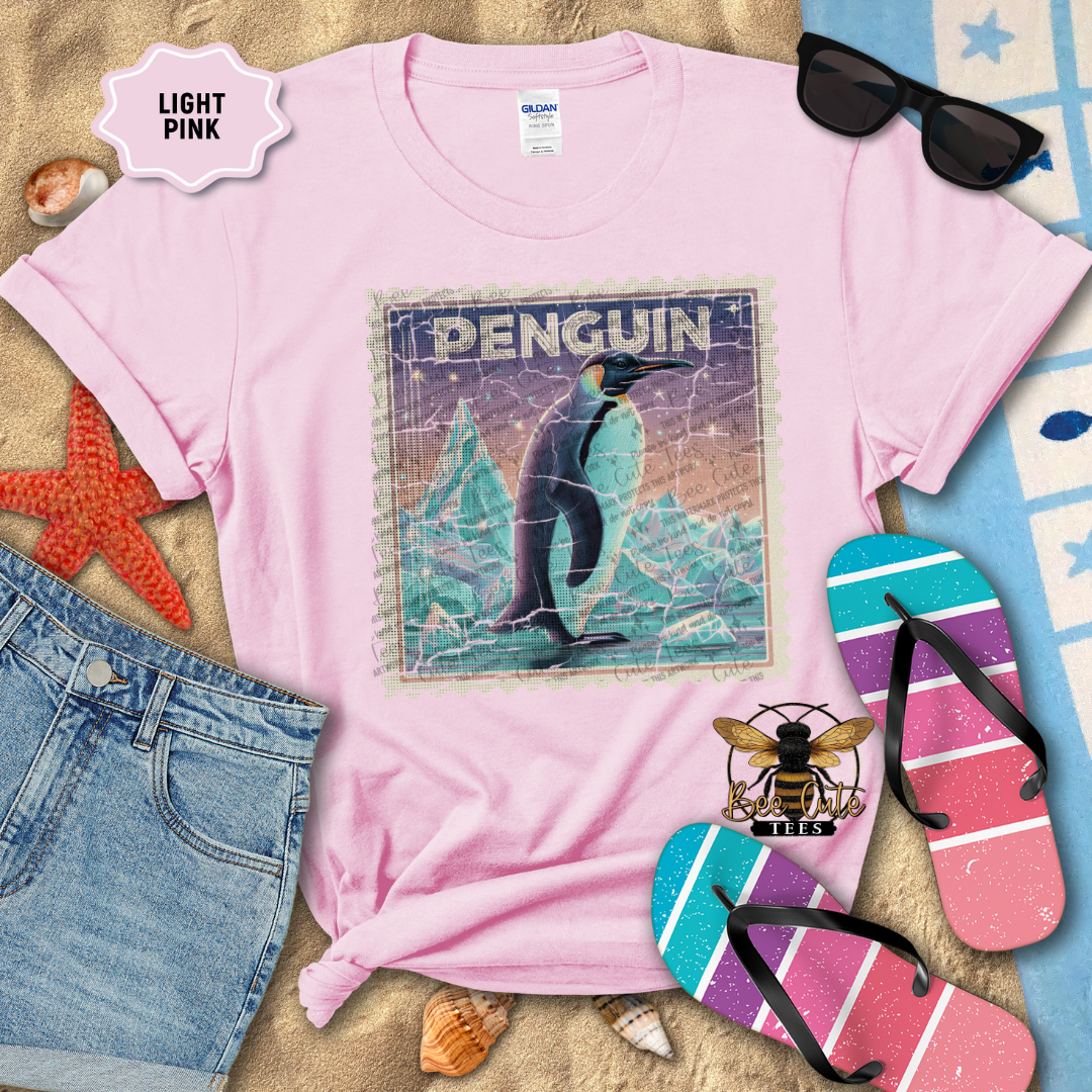 Light pink t-shirt with penguin graphic design on a beach-themed background