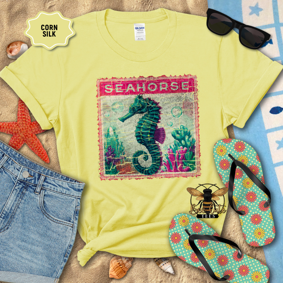 Yellow t-shirt with seahorse design, sunglasses, flip-flops, and beach items on a sandy background