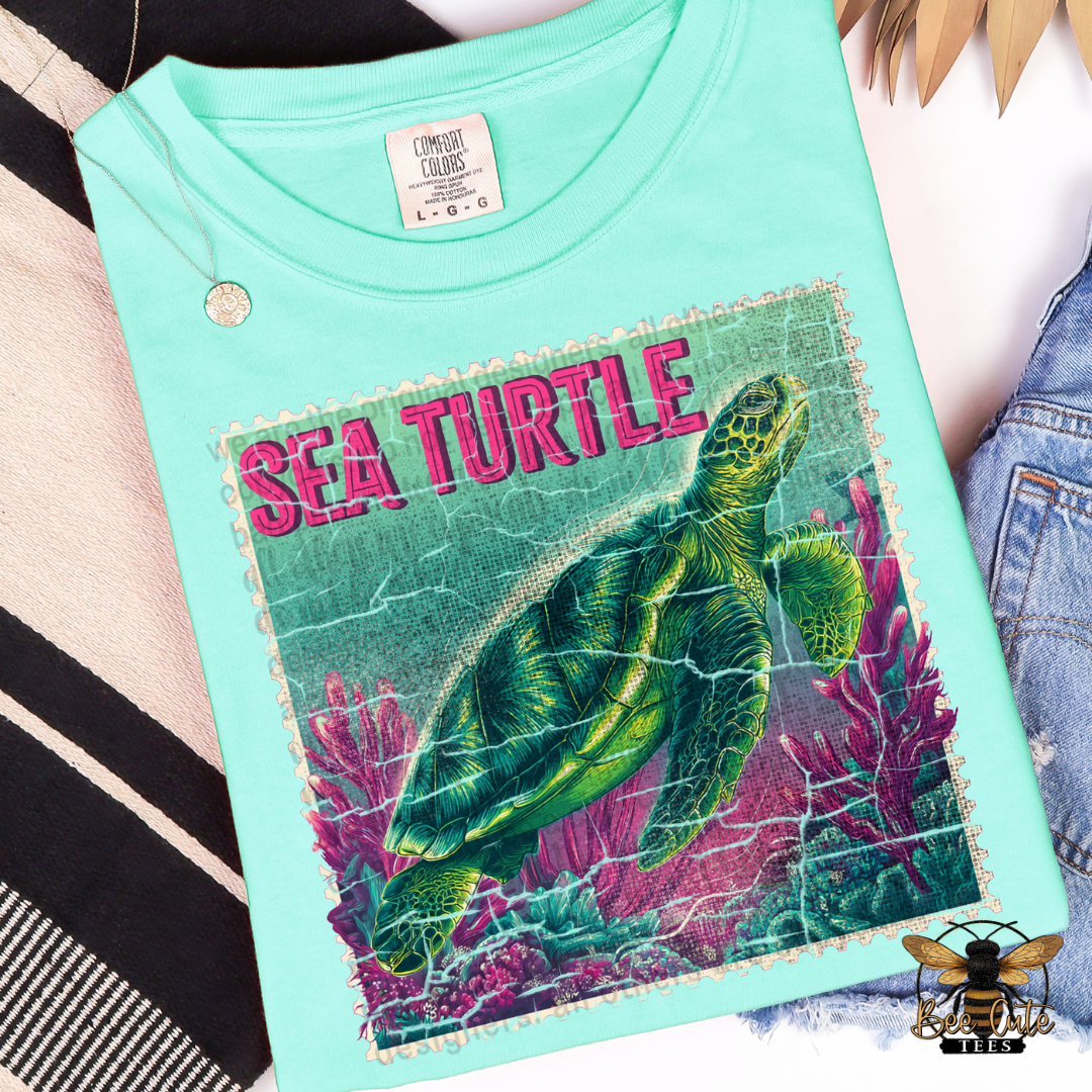 Mint green t-shirt with a sea turtle graphic and 'Sea Turtle' text on a striped fabric background.