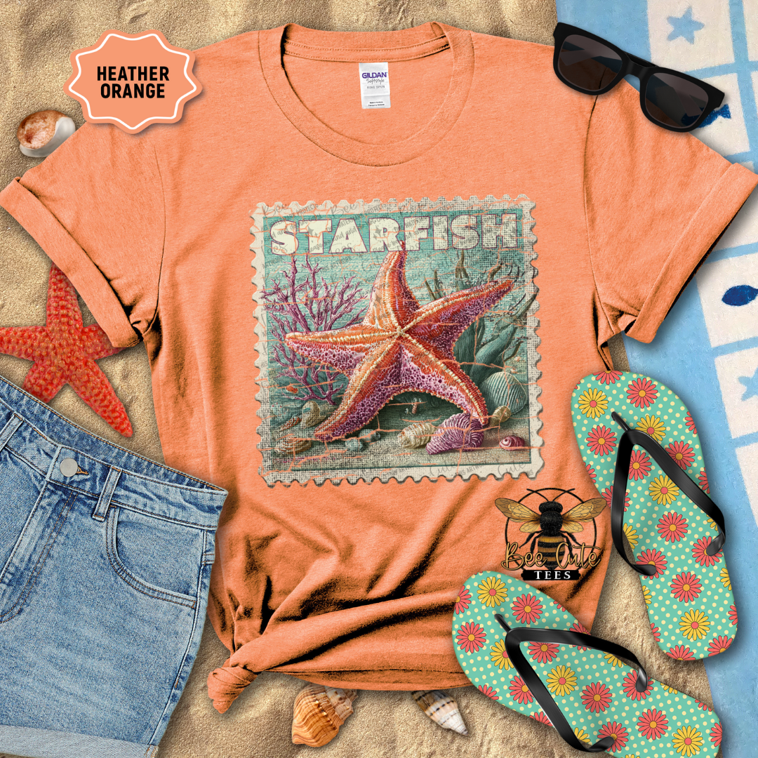 Heather orange t-shirt with starfish design, sunglasses, jeans, and flip-flops on a beach-themed background.