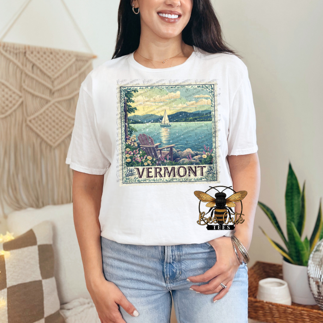 Person wearing a white t-shirt with a Vermont graphic design in a home setting.