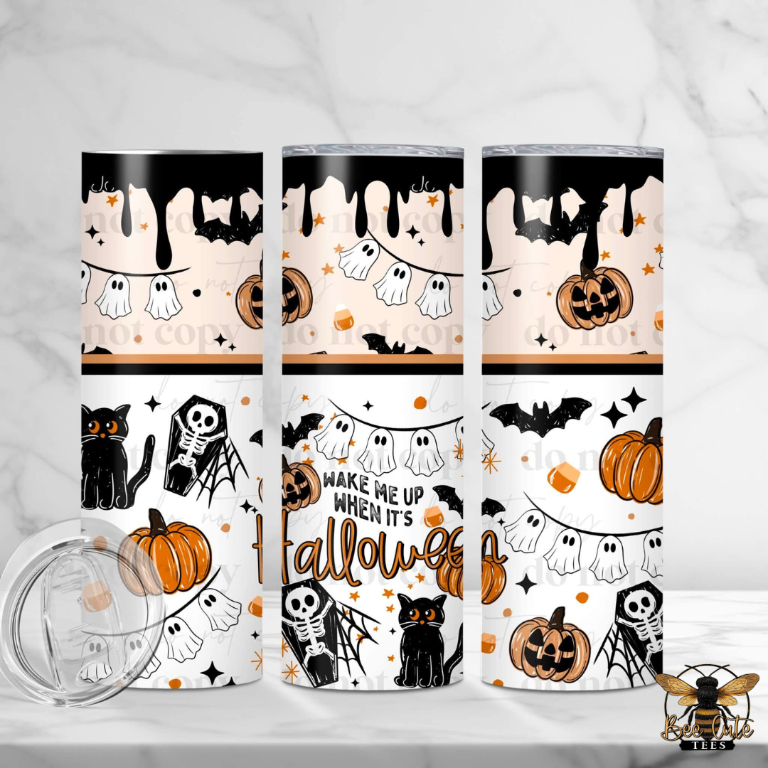 Three Halloween-themed stainless steel tumblers with a clear lid, displayed on a white marble surface. The tumblers feature a repeating pattern of orange pumpkins, black bats, white ghosts, black cats, and skeletons in orange and black.