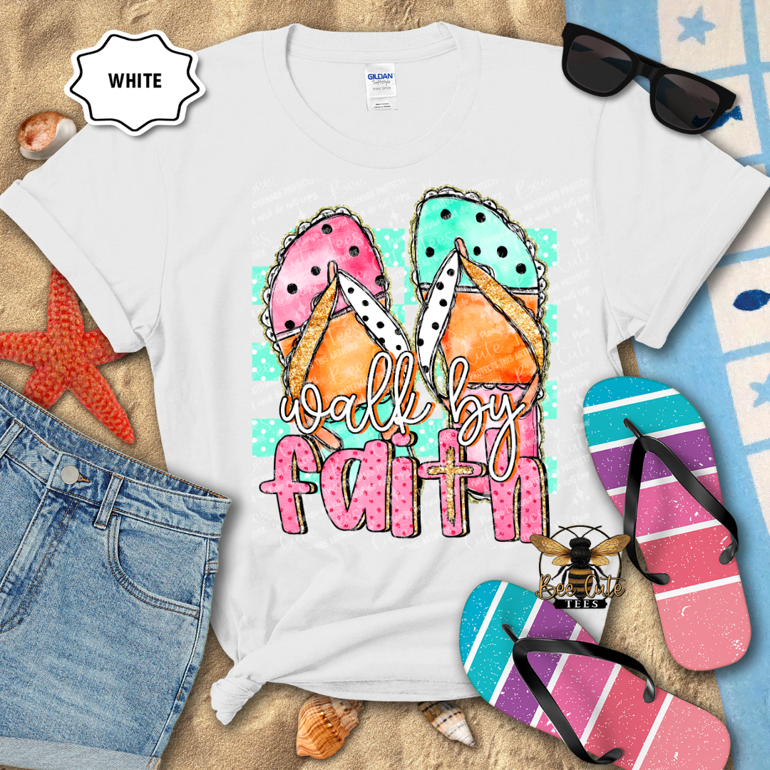 White t-shirt with 'walk by faith' design, sunglasses, denim shorts, and flip-flops on a textured surface.