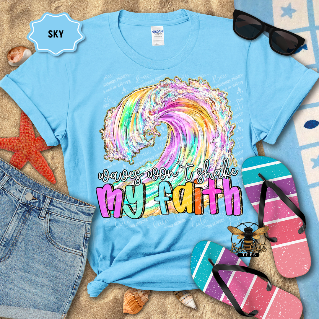 Light blue t-shirt with colorful wave design and text, surrounded by beach items.