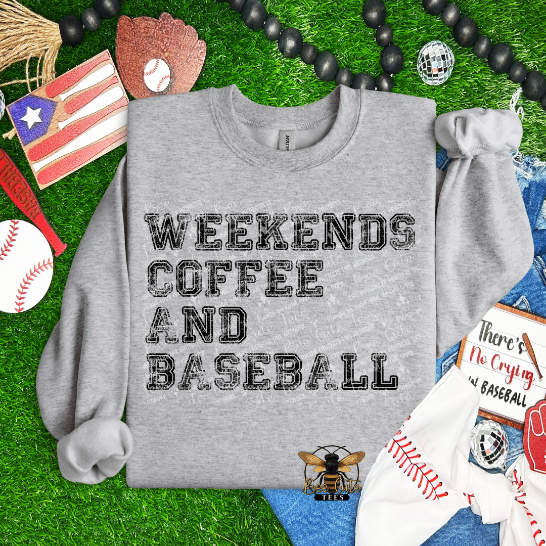 Gray sweatshirt with 'Weekends Coffee and Baseball' text on a grass background with sports-themed items.