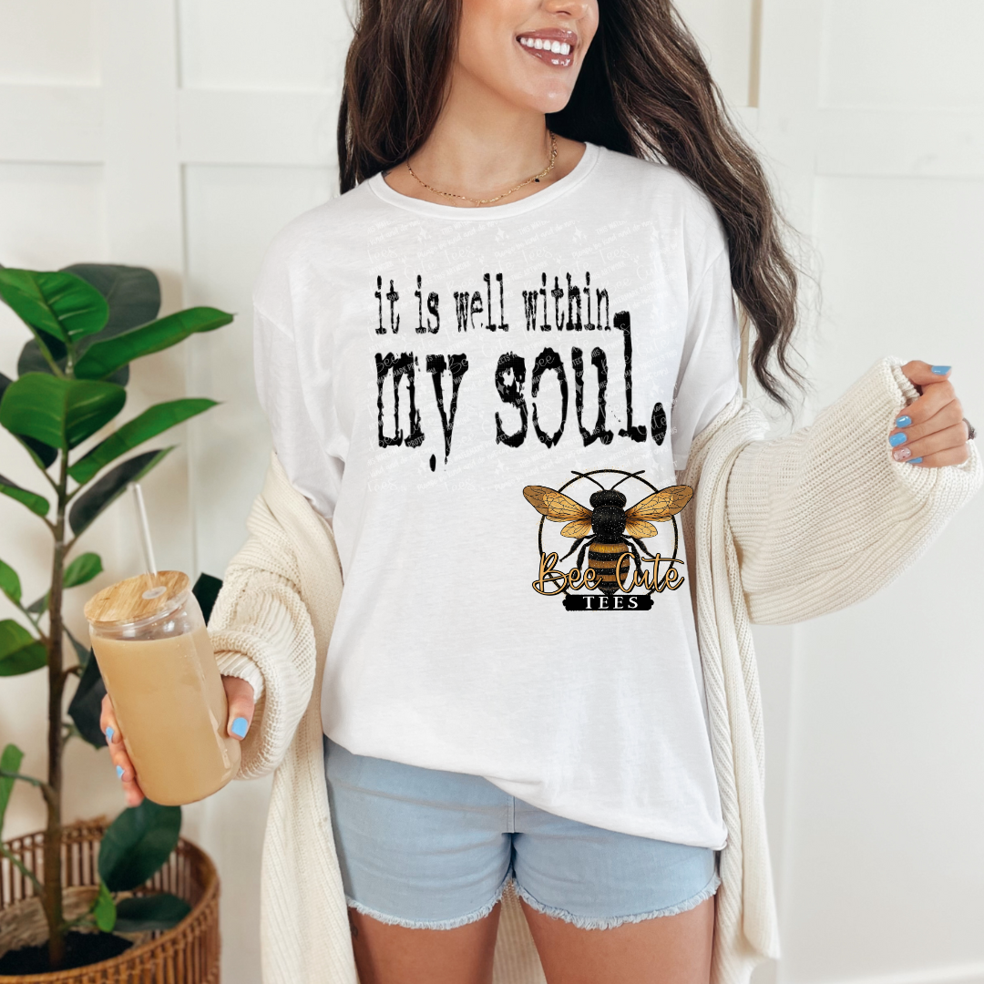 Woman wearing a white t-shirt with a bee logo and text, holding a drink.
