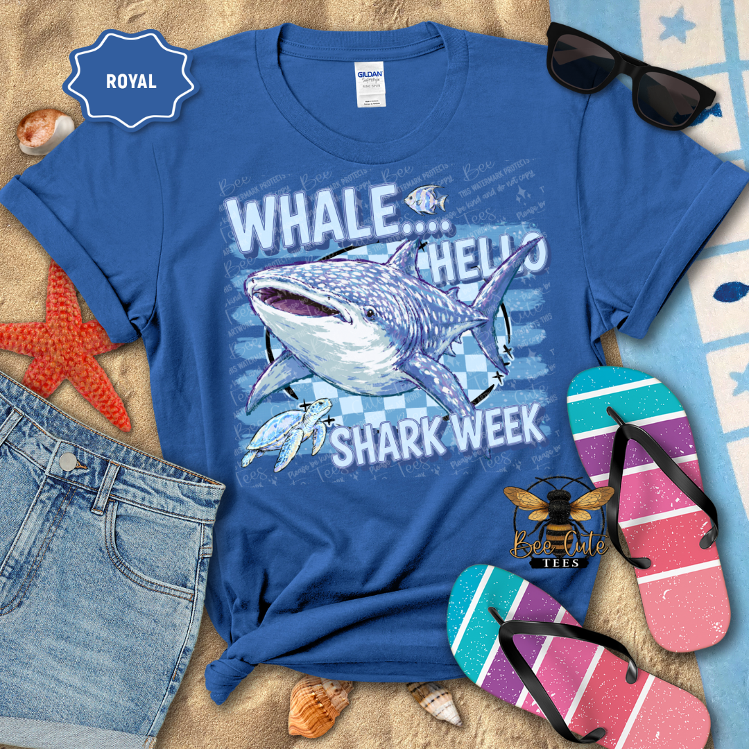 A royal blue graphic t-shirt featuring a shark and whale illustration with the text 'WHALE.
