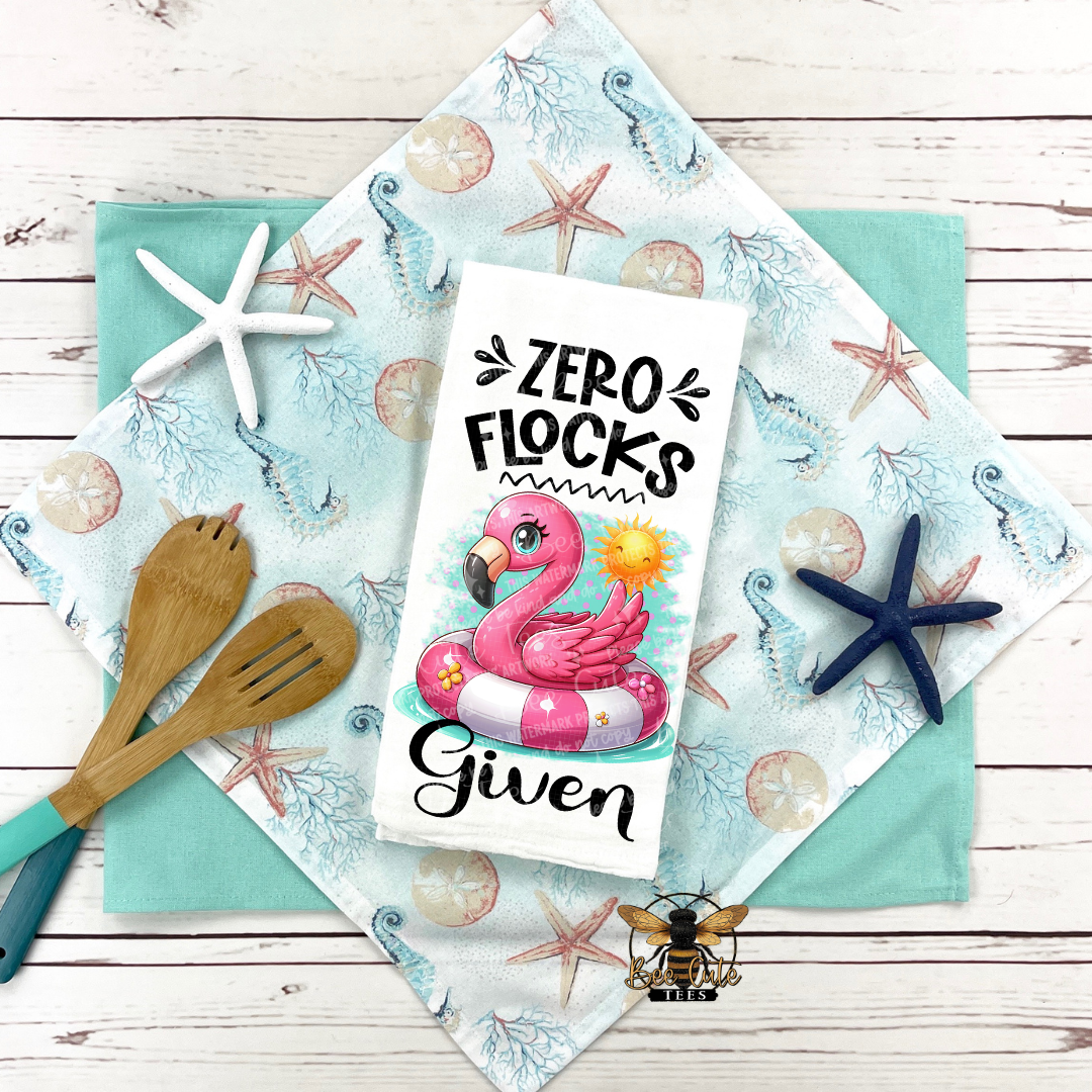 Flamingo-themed card with 'Zero Flocks Given' text on a decorative cloth with starfish and seashell pattern.